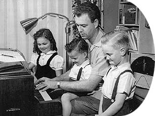 Photograph: Nelson Riddle playing piano with his three children looking on.